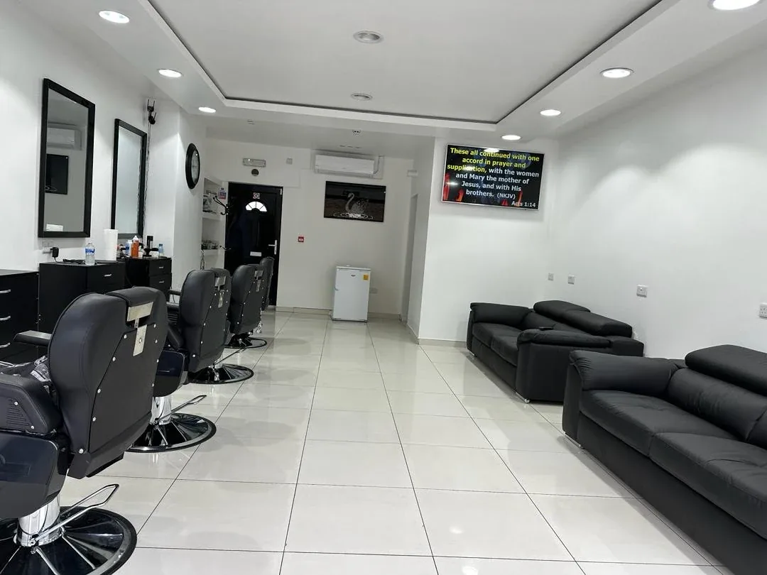 Bright, spacious interior of Clippers Barbers with black chairs and white walls